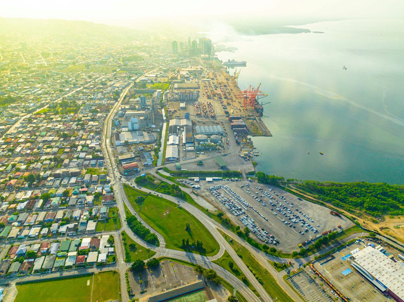 Aerial view of Port of Spain, Trinidad, with container cranes, warehouses, a car park and homes beside the Gulf of Paria