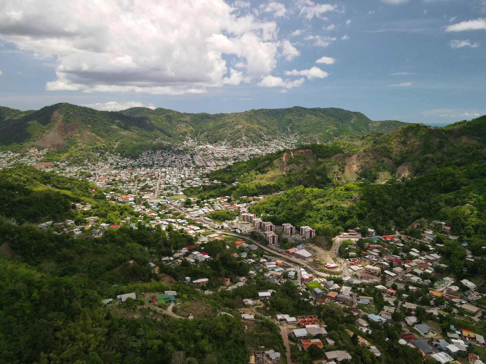 Aerial view of houses and apartment blocks in a green hill-ringed valley in Trinidad and Tobago